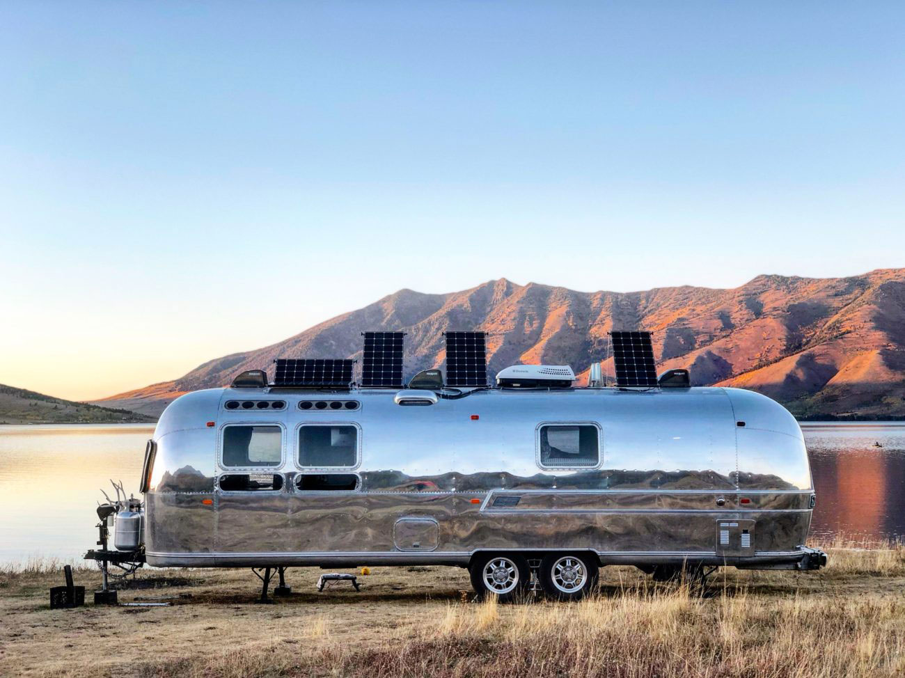 Solar panels charging on Airstream trailer with Blue Sky Energy MPPT charge controllers next to lake and mountains in Yellowstone National Park